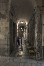 Young family in an old town alley in the evening, Genus, Italy
