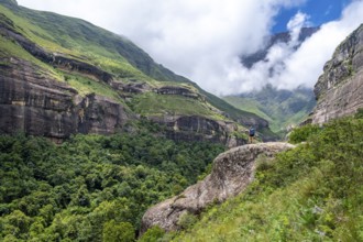 Female hiker standing in front of landscape with mountains and fog, Drakensberg National Park,