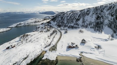 Aerial view of a serene Nordic landscape showcasing a snow-covered coastline, winding road, and