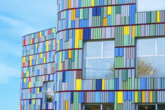 A stunning view of a modern building's curved facade adorned with multicolored panels. Bright