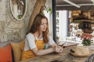 A mature woman tourist uses a smartphone while relaxing at a cafe in Cesme, Turkey. She enjoys her