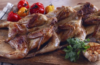 Grilled quail meat, on a wooden chopping board, tobacco, in the oven, with spices, homemade,