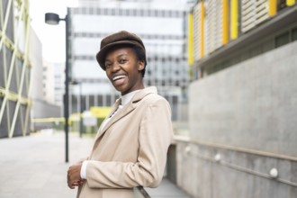 A stylish black woman smiles confidently while standing in a modern urban environment Her chic