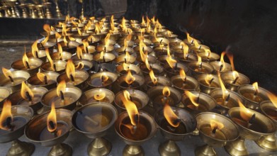Many burning oil lamps produce a warm, glowing ritual light, Bodnath, Kathmandu, Nepal