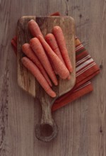 Fresh carrots on a chopping board, wooden table, raw carrots, no people