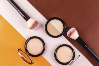 Flat lay of makeup brushes and face powders on a vibrant tricolor background. The contrasting
