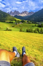 Tourist resting on a green meadow, enjoying the breathtaking view of the idyllic valley and the