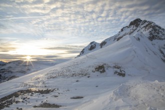 Scenic winter landscape with snow-covered mountains perfect for ski touring. The sunrise casts a