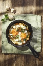 Fried eggs with spinach, mushrooms, grated cheese and feta cheese in small cast iron skillet. Top