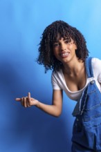 Young woman with curly hair pointing her finger to the left side of the frame while smiling on a
