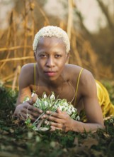 A serene woman lies in the grass, surrounded by delicate snowdrops in Tacony Creek Park. Her