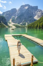 Woman enjoying a sunny summer day at lake braies, with the stunning seekofel mountain rising