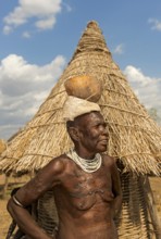 Woman with scar tattoo on her upper body carrying a calabash drinking bowl on her head, ethnic