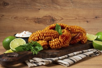 Corn ribs, with cream sauce, spices and lime, appetizer, on a wooden cutting board, homemade, no