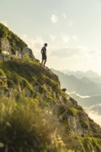 A lone man stands on a scenic mountain trail, taking a moment to rest during an invigorating run.