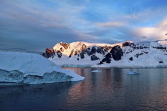 Iceberg and mountains reflected in the water at dusk, icebergs in the Southern Ocean in Antarctica