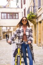 Pretty latin woman with sunglasses doing bicycle sightseeing in the city through the old town. Eco