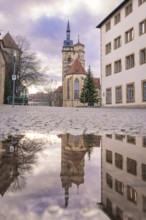 Reflection of a church in a puddle with a cloudy sky, collegiate church Stuttgart, Germany