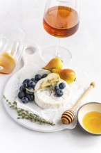 Elegant cheese platter with creamy brie, ripe pears, and juicy blueberries, accompanied by a glass