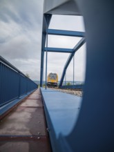 Yellow train through steel bridge taken from an unusual angle, track construction, rail delivery