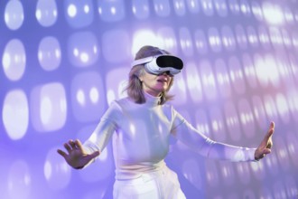 An elderly Asian woman experiences the metaverse through a virtual reality headset, surrounded by a
