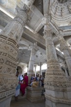 Indian woman praying between the white marble pillars in the Adinath temple in Ranakpur, Jain