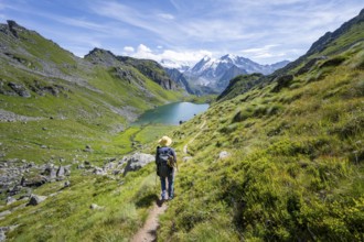 Mountaineer on hiking trail in picturesque mountain landscape, view of mountain lake Lac du Louvie