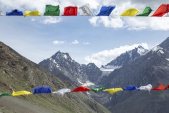 Colorful prayer flags flutter in the foreground, set against the breathtaking backdrop of the