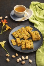 Traditional iranian dessert sohan with cup of green tea on a black concrete background and green