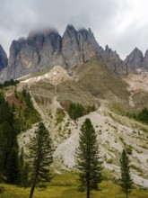 Geisler peaks rise above the rock layers into the cloudy sky, Villnöss Valley, Sass Rigais,