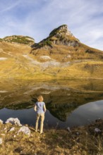 Lake Augstsee and the Atterkogel mountain on the Loser. A hiker stands on the shore. Autumn, good