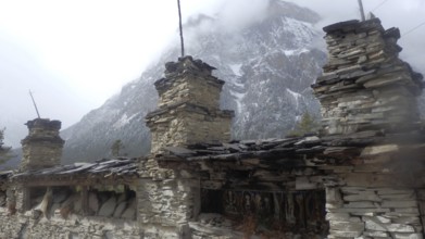 Stone structures in front of a misty mountain landscape, cold and calm atmosphere, trekking at