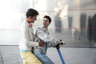 A cheerful gay couple enjoying a scooter ride together on a sunny day, wearing casual outfits.