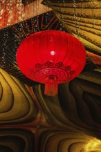 A vivid red lantern adorned with intricate patterns hangs in the festive atmosphere of a Taoist and