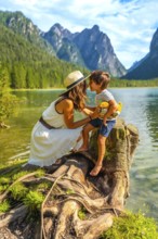 Mother and son bonding on the shore of a picturesque alpine lake, surrounded by breathtaking