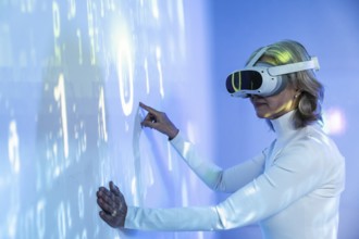 An elderly Asian woman interacts with a virtual environment, wearing a VR headset. She engages with