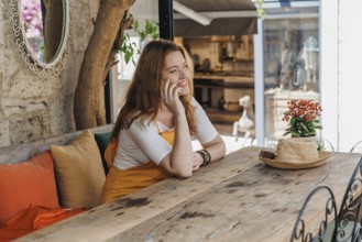 A mature woman, wearing an orange and yellow outfit, enjoys a phone call during her vacation in an