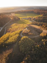 Aerial view of hills and fields surrounded by autumnal forests, Lindenrain industrial estate,