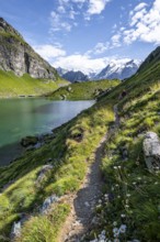 Mountaineer on a hiking trail at a mountain lake with a view of glaciated mountain peaks, Lac du