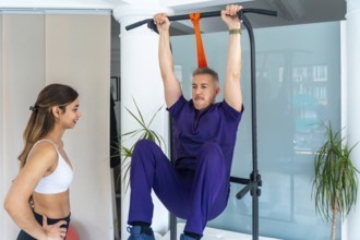 Physiotherapist observing a man performing leg raises on a pull up bar, engaging in medical