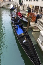 Gondoliers waiting for customers at their gondolas, Venice, Veneto, Italy