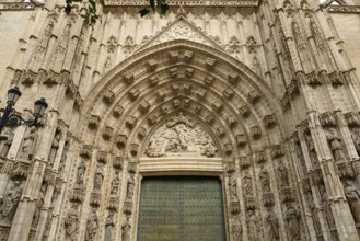 Elaborately decorated Gothic entrance door with detailed architectural elements, Seville,