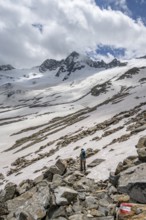 Mountaineer on a hiking trail between snow, descent from the summit of Schönbichler Horn, view of