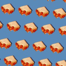A creative pattern of sandwiches with vibrant red floral fillings set against a bright blue