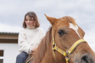A young girl enjoys a peaceful day at the farm, riding a gentle horse. The scene captures the joy
