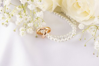 Elegant wedding rings lie nestled among delicate white roses and dainty baby's breath. The