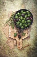 Chalkidiki olives, classic Greek green olives, in a bowl on a cutting board, top view, without