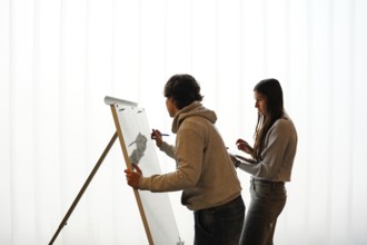 Two teenagers, a non-binary individual and a female, participate in an writing activity, o a