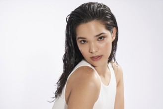 A striking female model with wet hair looks at the camera, showcasing a natural beauty look in a