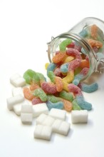 Lots of colorful jelly sweets in glass containers and sugar cubes, sugar consumption